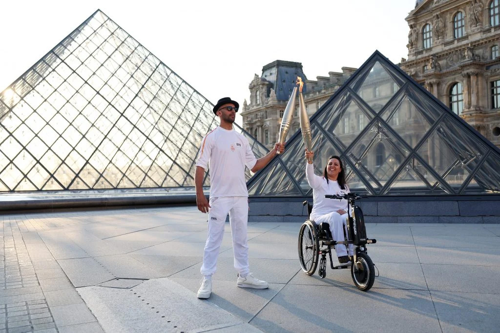 Artist JR Carries the Olympic Torch Through the Louvre